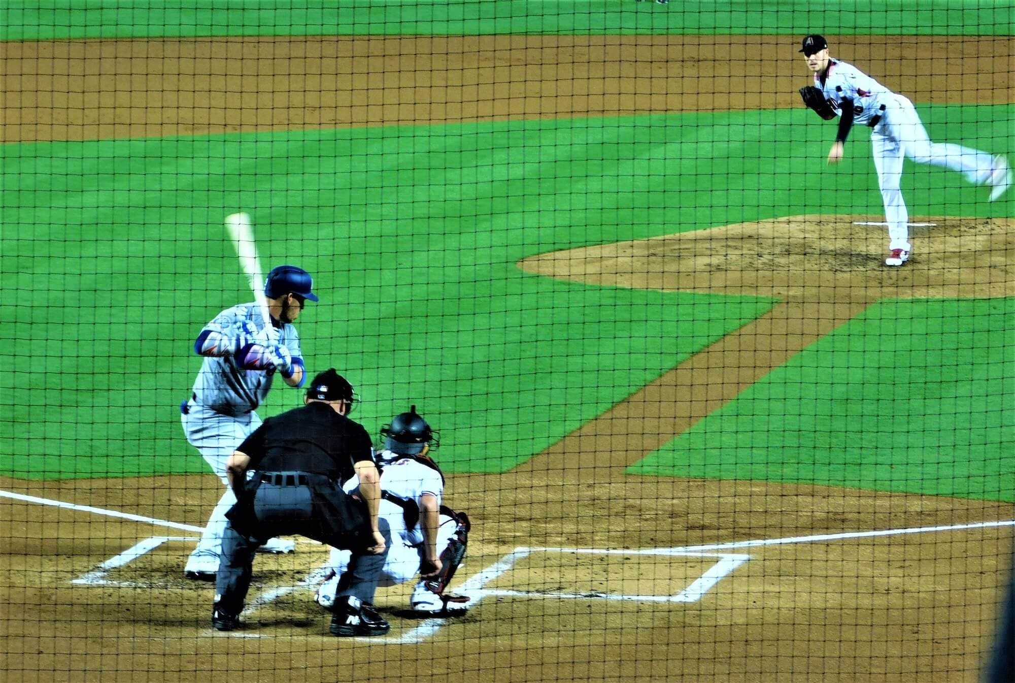 Baseball pitcher and batter seen through the backstop netting during a night game